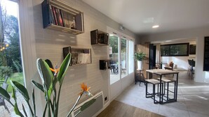 Una cocina moderna con paredes de ladrillo blanco, estantes integrados y un comedor con mesa y sillas de madera.