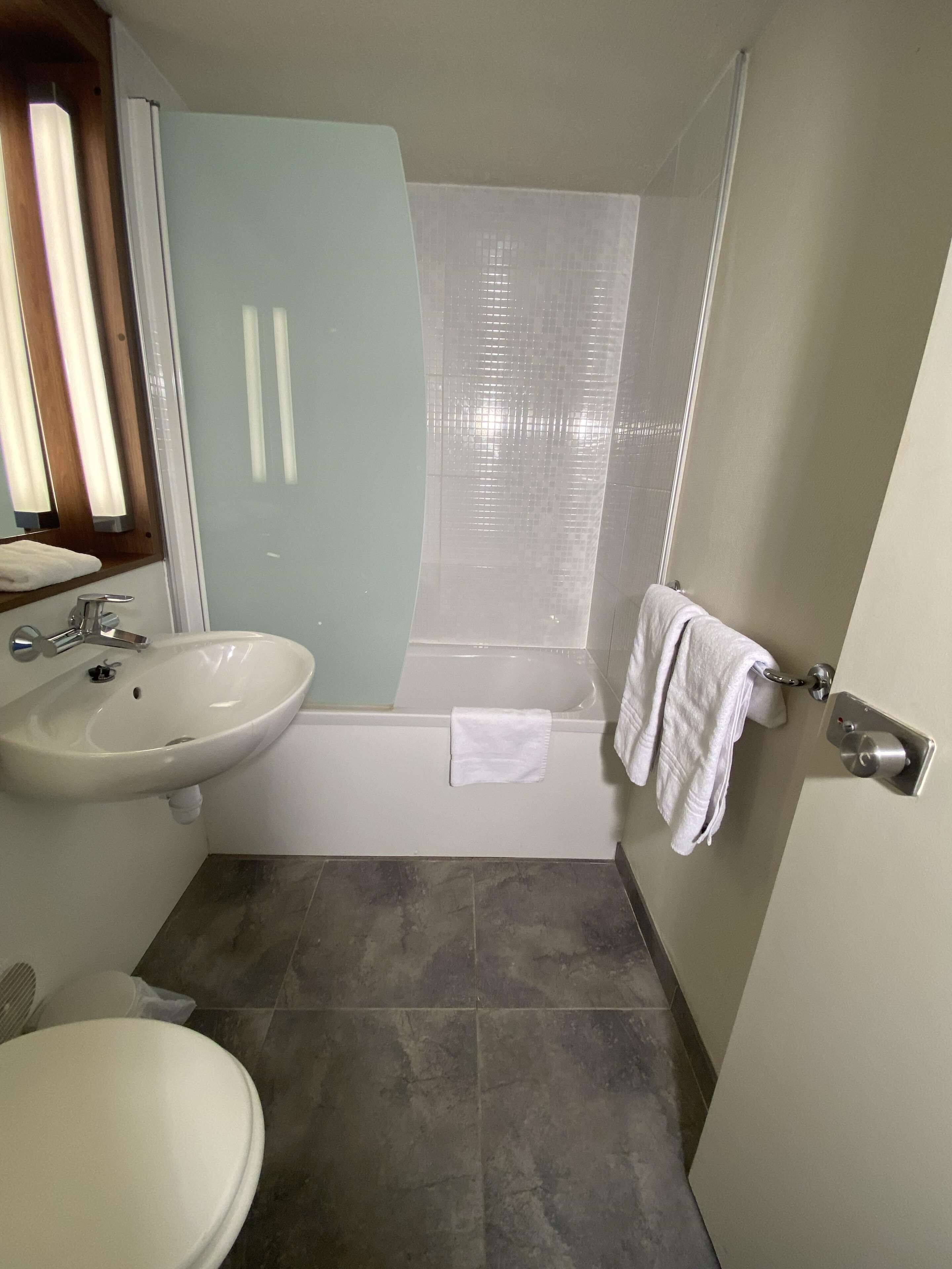 Een badkamer met wastafel, toilet en bad.