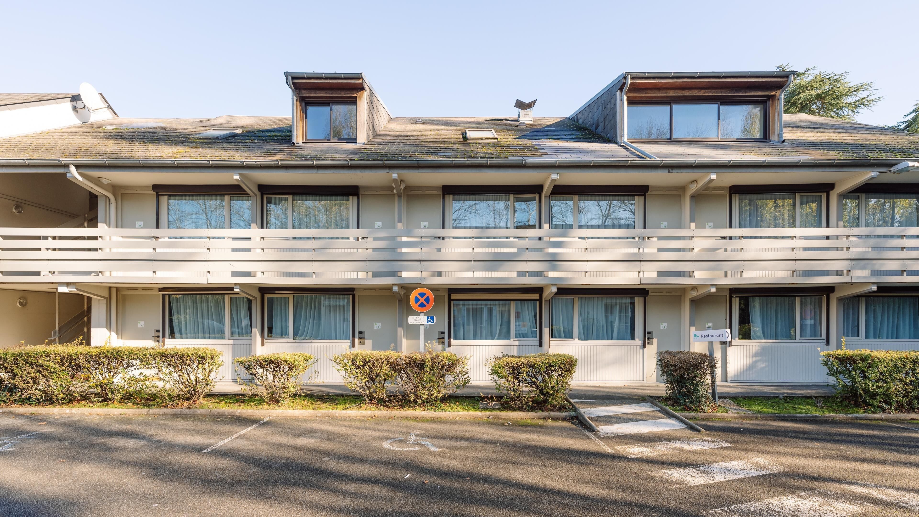 Un edificio de varios pisos con techo plano, ventanas grandes y un letrero que indica un restaurante.