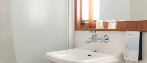 A bathroom with a white sink, chrome faucet, and a mirror with wooden trim.