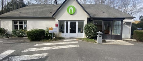 Un edificio con un logotipo verde, una zona de recepción y un cartel que indica hotel de primera clase.