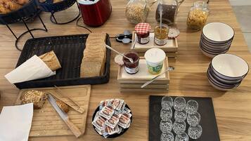 A breakfast setup with bread, pastries, and condiments on a wooden table.