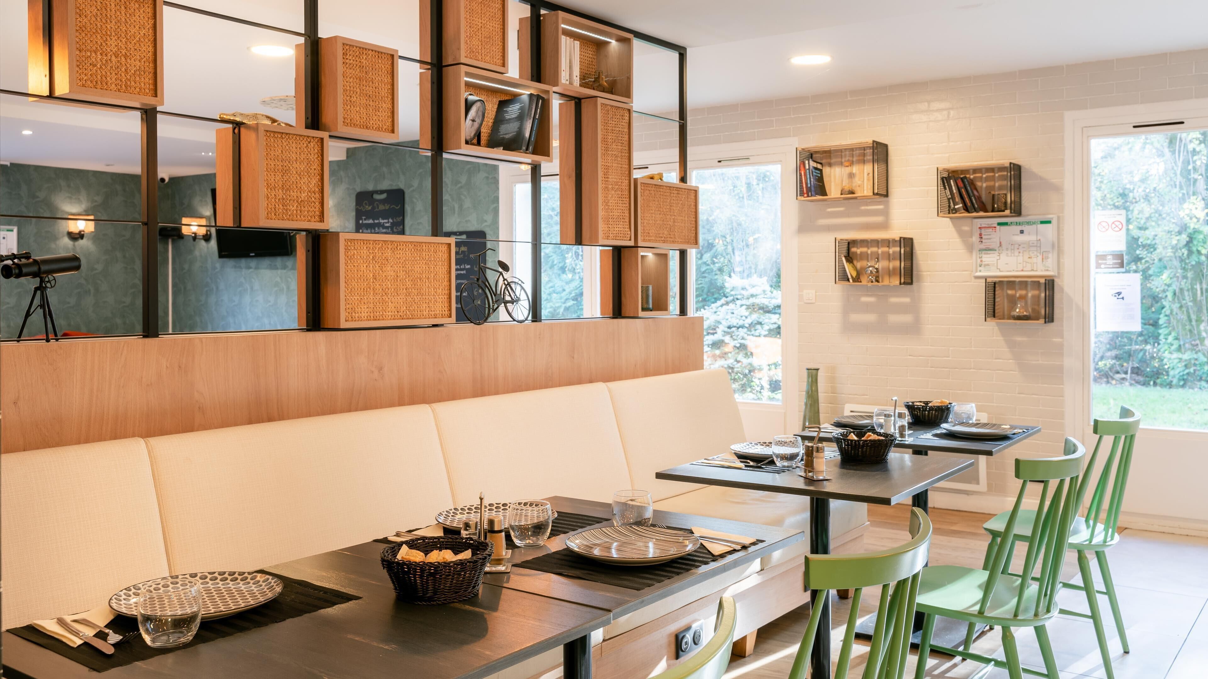 A modern dining area with a wooden wall, a sofa, and a dining table set with plates, glasses, and baskets.