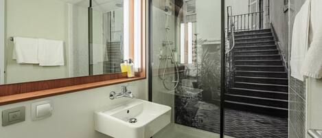 Un baño moderno con cabina de ducha de vidrio, un lavabo blanco y un espejo grande.