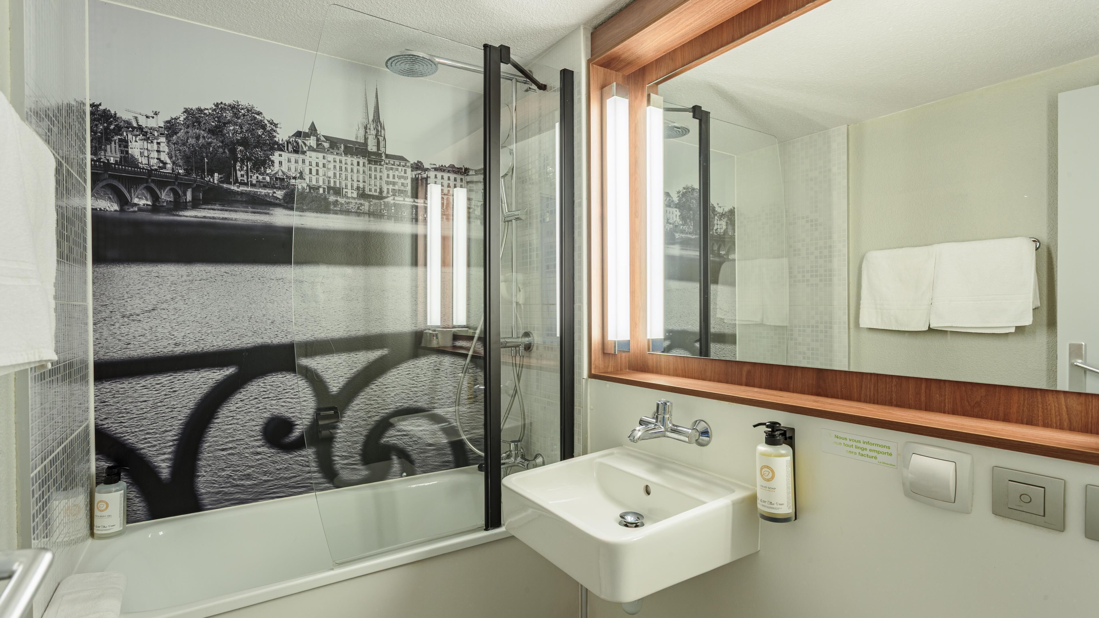 Baño con cabina de ducha de vidrio, lavamanos y espejo.