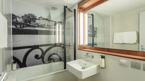 A bathroom with a glass shower enclosure, a sink, and a mirror.