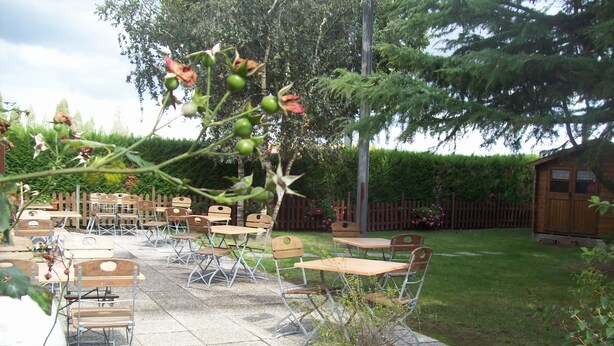 An outdoor patio with tables and chairs, surrounded by a wooden fence and a garden. - Hotel Campanile Nantes Ouest - Saint Herblain (Saint-Herblain)