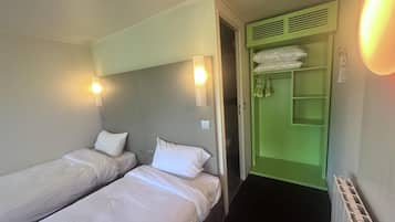 Et hotelværelse med to enkeltsenge, et grønt skab og en radiator.