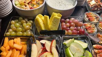 Buffet com diversas frutas, legumes e sobremesas.