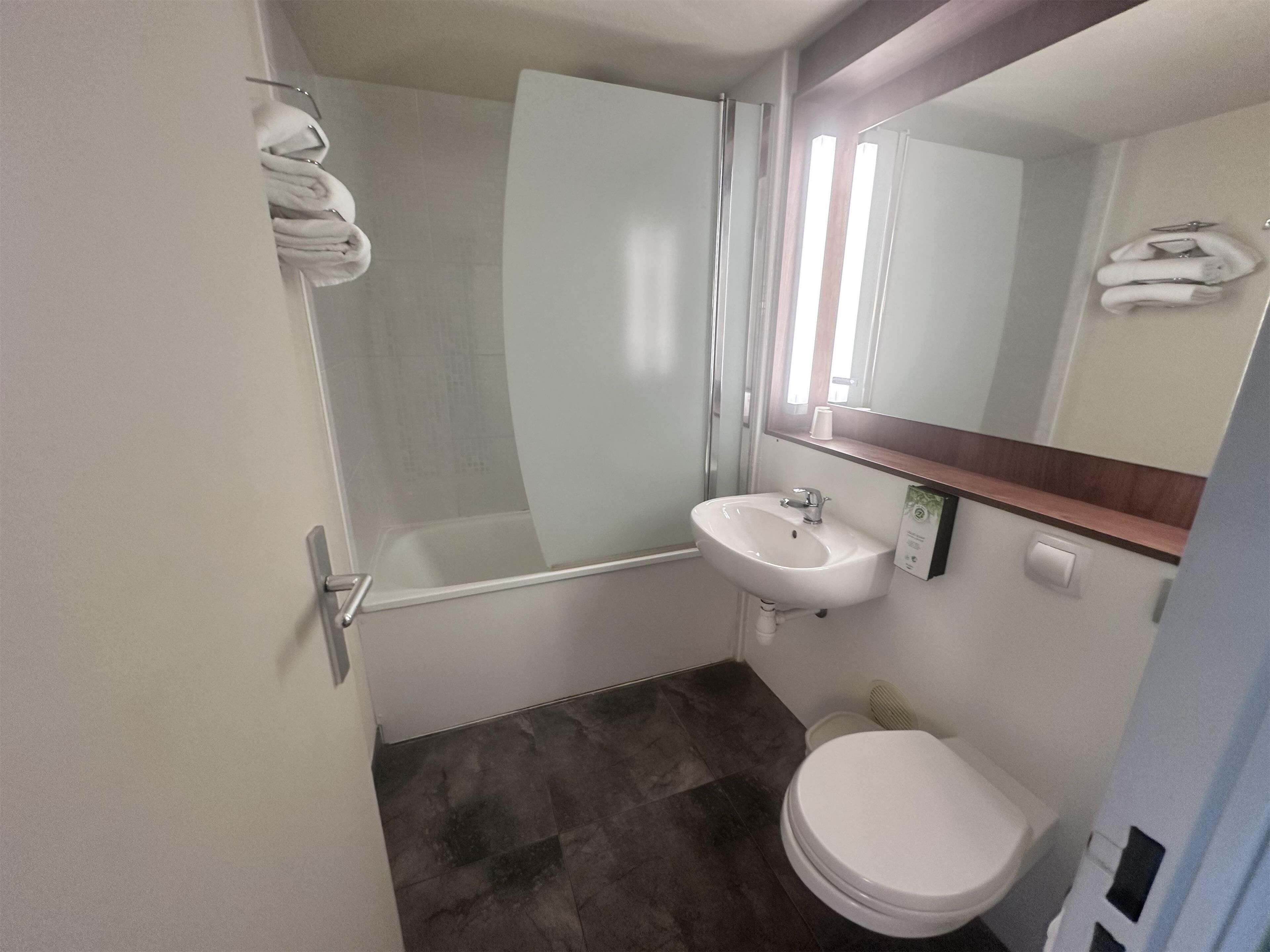 Ein Badezimmer mit weißem Waschbecken, Toilette und einer Duschkabine aus Glas.