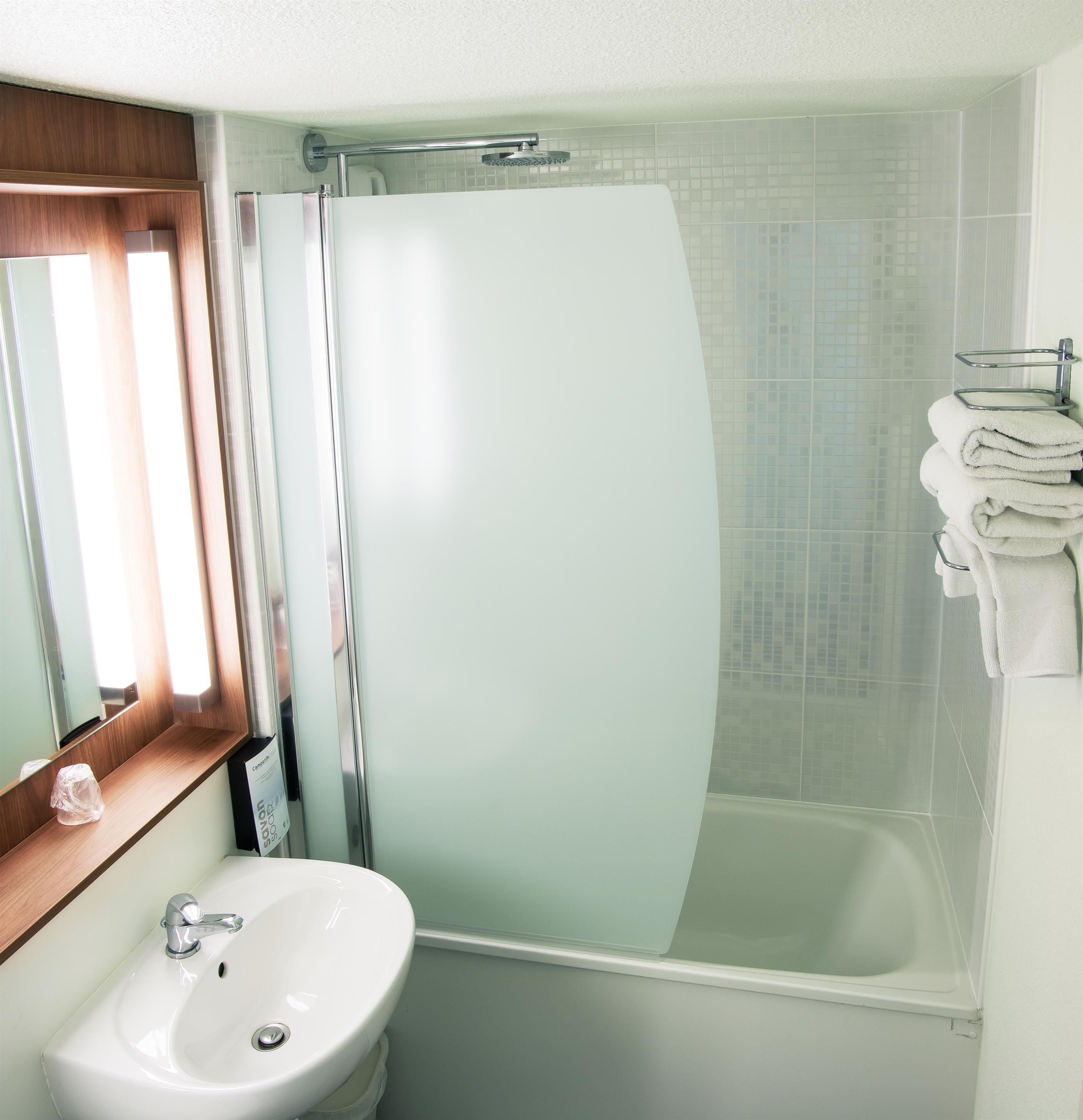 A modern bathroom with a glass shower enclosure, a white sink, and a towel rack.