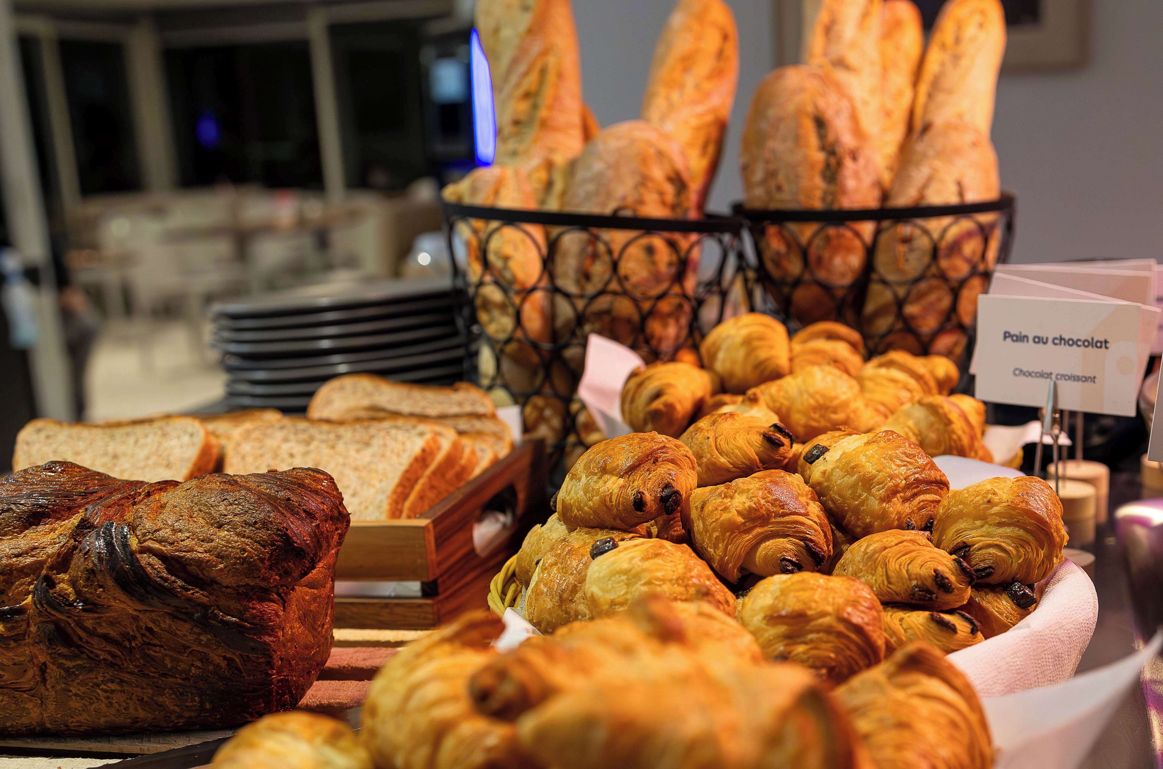 A variety of baked goods including bread and croissants displayed in baskets.