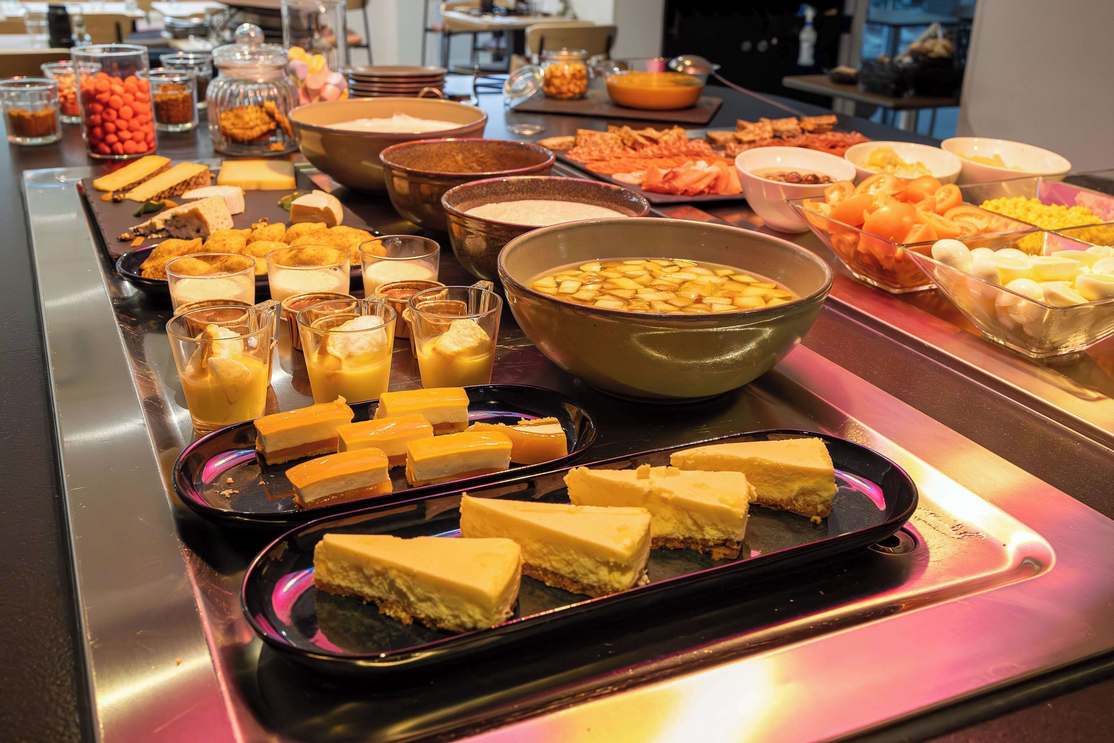 A buffet with various food items including cheese, fruits, and desserts.