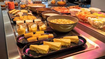 Un bufé con diversas opciones de comida, incluyendo queso, frutas y postres.
