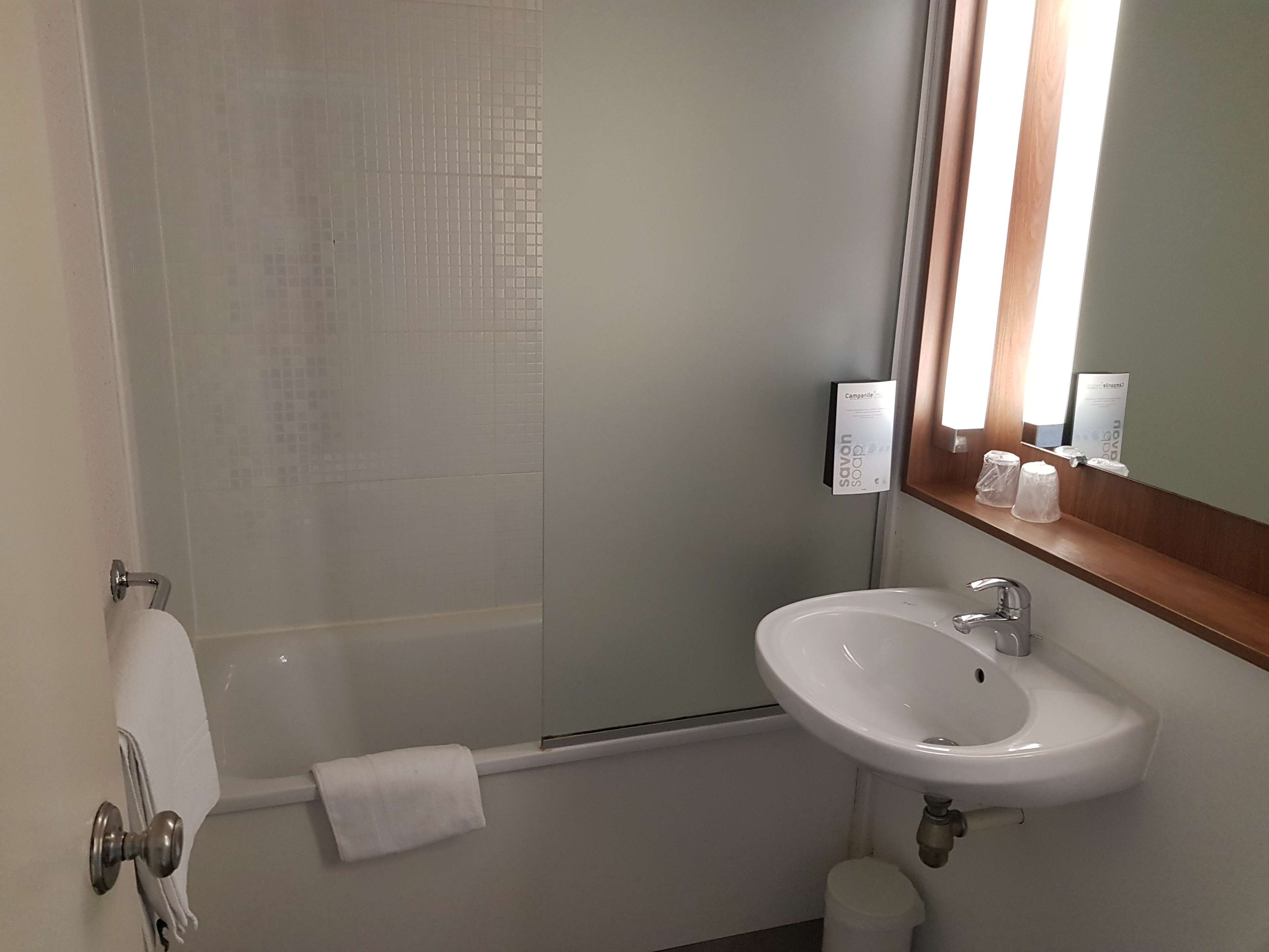 A bathroom with a white sink, a mirror, and a shower.