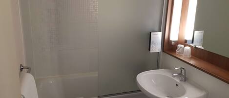 A bathroom with a white sink, a mirror, and a shower.