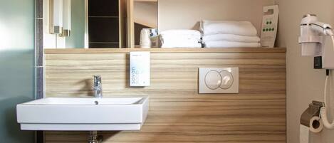 A modern bathroom with a sink, mirror, toilet, and towel rack.