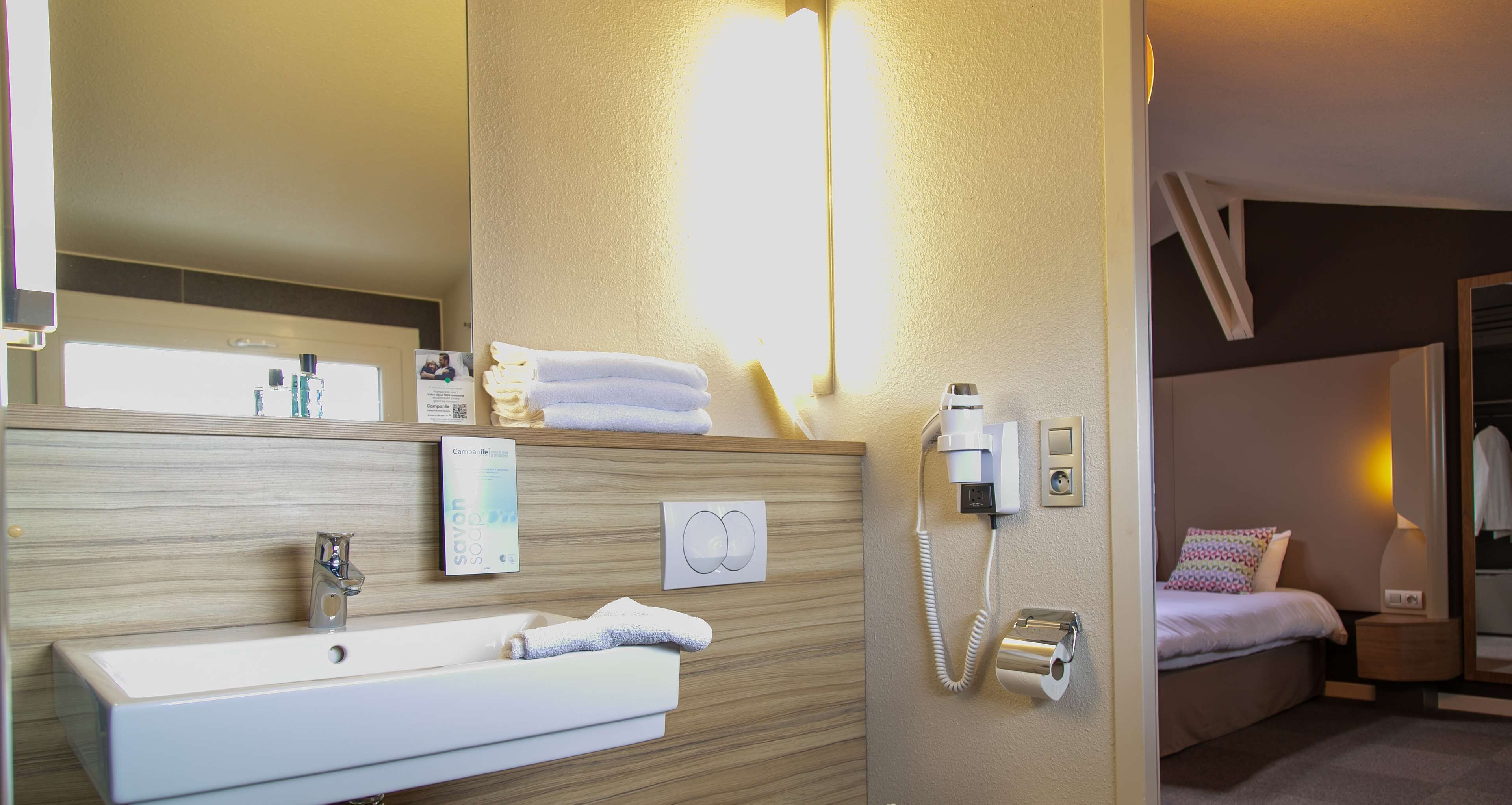 A hotel bathroom with a sink, mirror, toiletries, and a telephone.