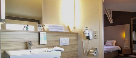 A hotel bathroom with a sink, mirror, toiletries, and a telephone.