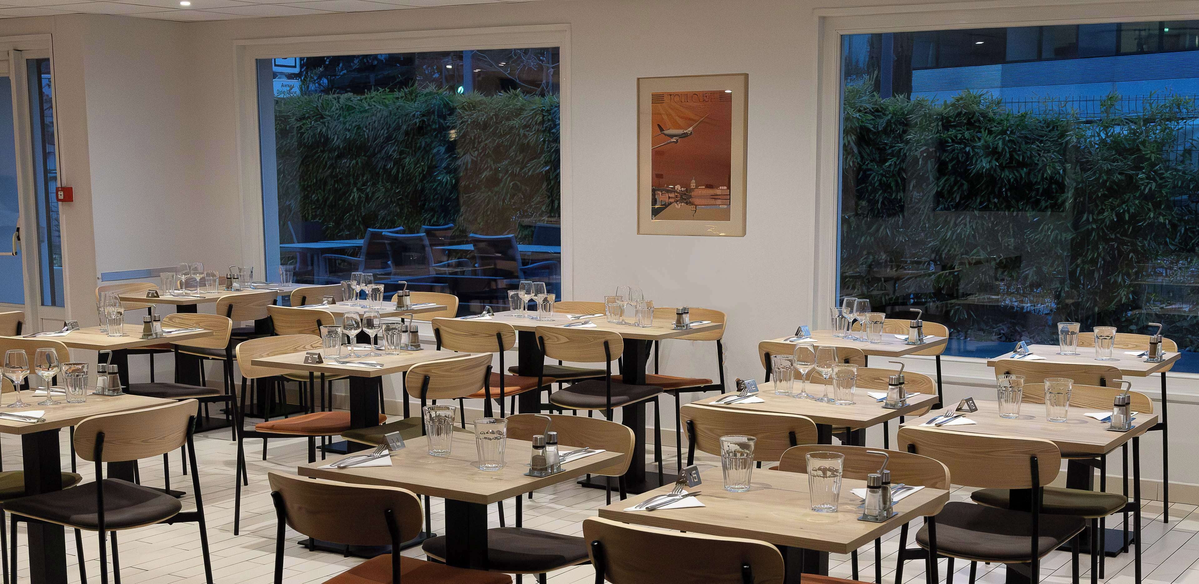 A restaurant with multiple tables and chairs, each set with glasses and cutlery.