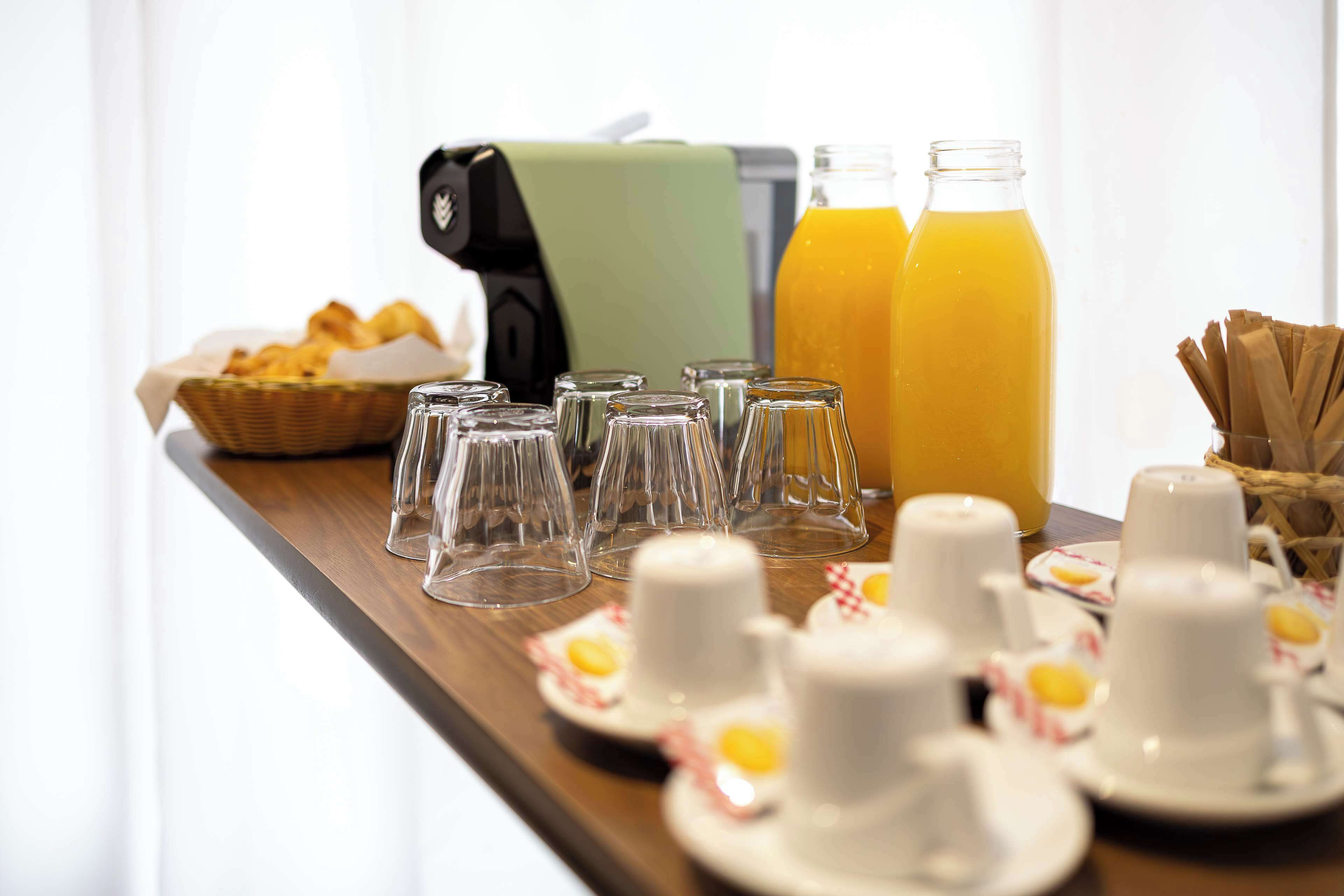 Un buffet de petit-déjeuner proposant divers produits, notamment du pain, du jus et des tasses.