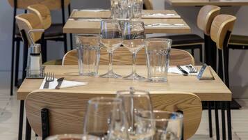 A restaurant setting with multiple tables, each set with glasses, cutlery, and napkins.