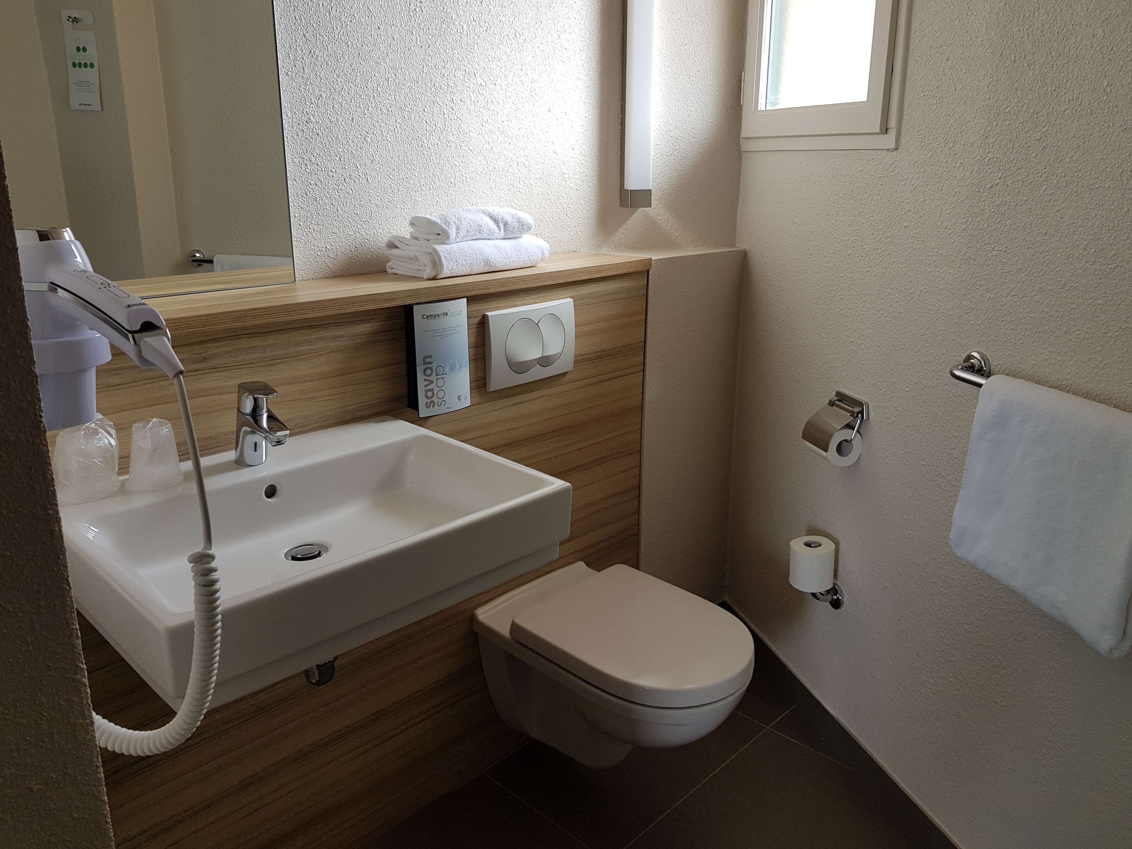 A modern bathroom with a sink, toilet, and towel rack.