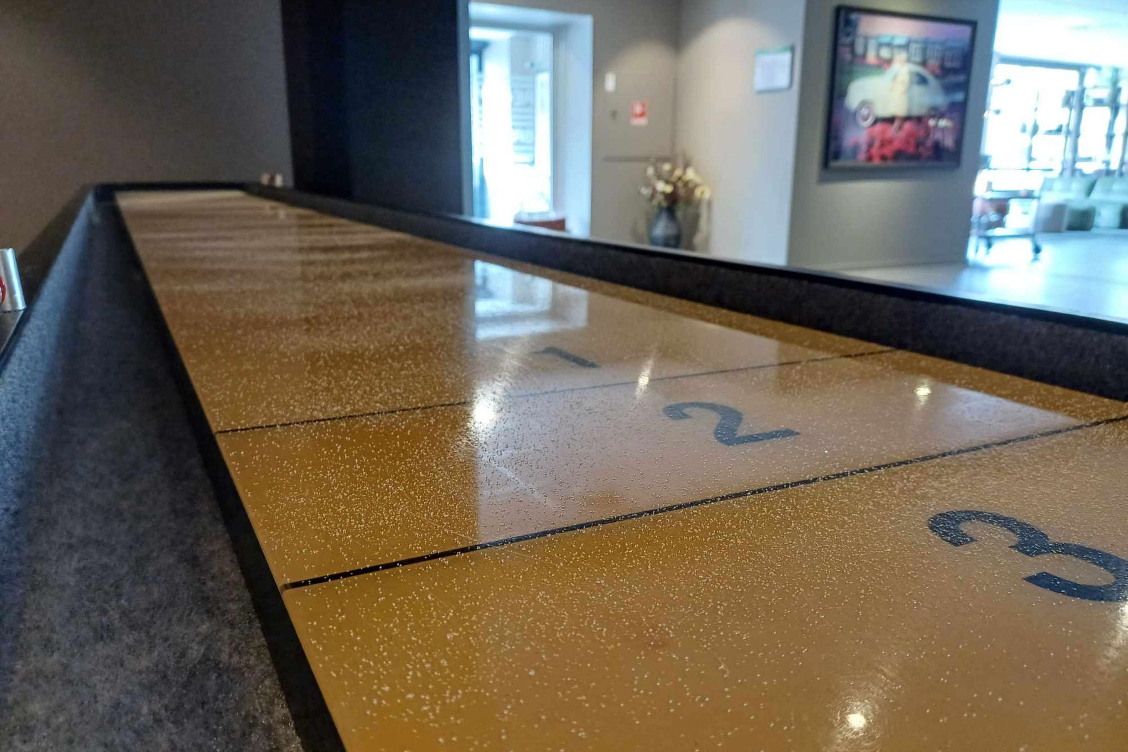 Een gepolijste, reflecterende vloer met genummerde secties, waarschijnlijk een bowlingbaan of een ander recreatiegebied in een hotel.