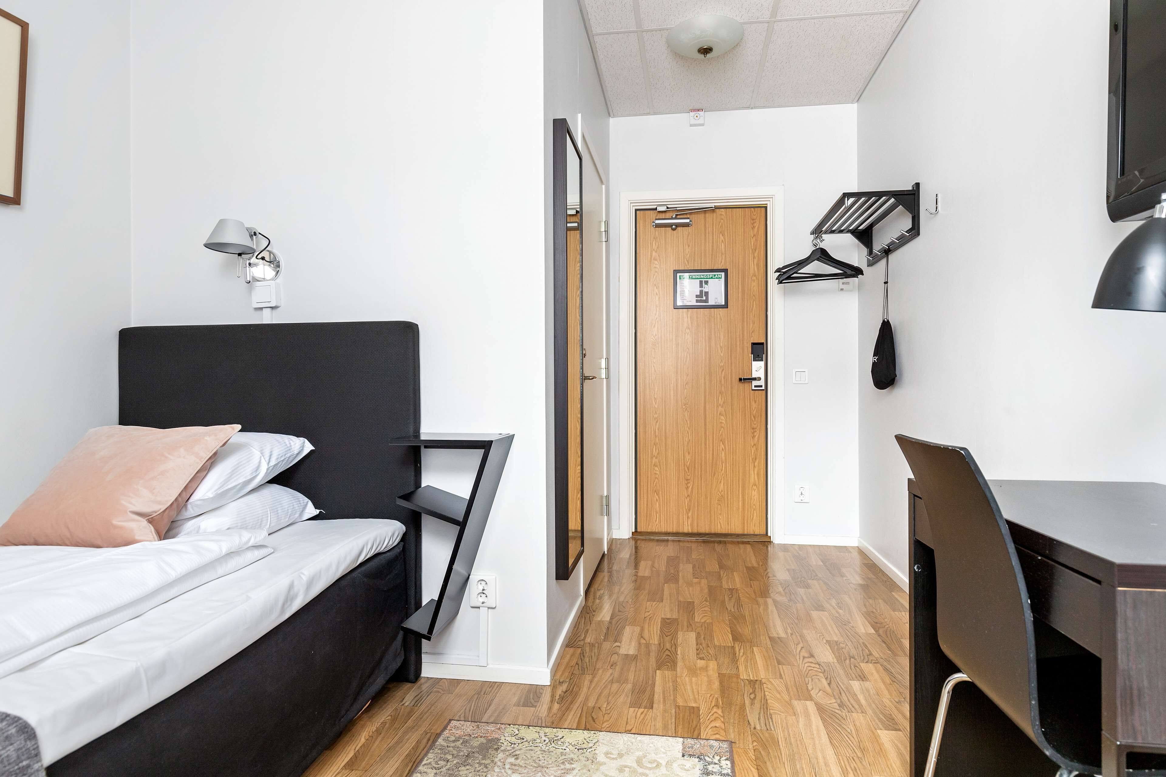 Une chambre moderne comprenant un lit, une table de chevet, une lampe et un bureau avec une chaise.