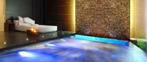 Un área de spa moderna con suelo calefaccionado, un sofá blanco con cojines y una pared con textura.