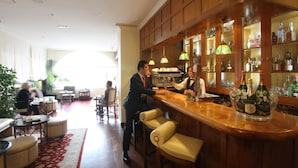 A bar area with wooden paneling, a bar counter, and a seating area with cushioned chairs. - Hotel Quinta de los Cedros (Madrid)