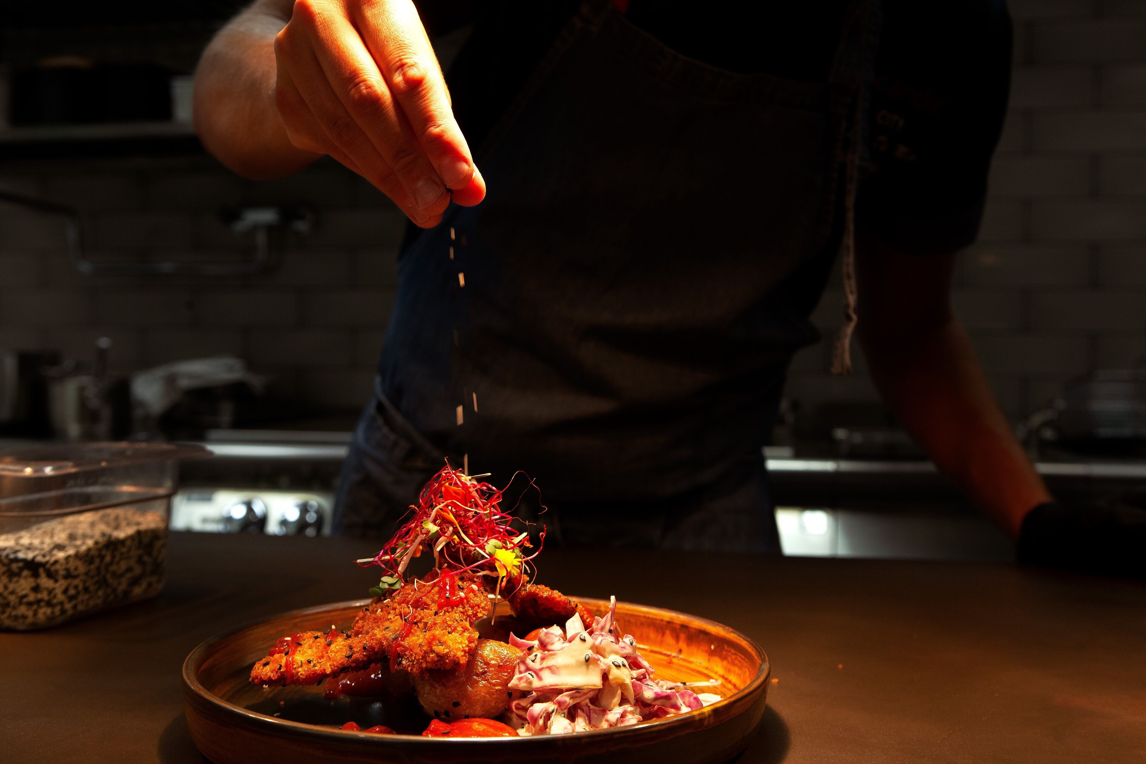 A person seasoning a dish with a variety of ingredients.