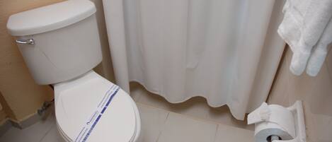 A white toilet with a paper towel holder and a roll of toilet paper.