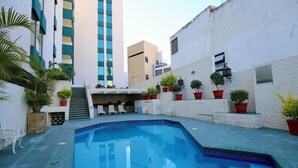 Una piscina con plantas en macetas y un banco blanco.