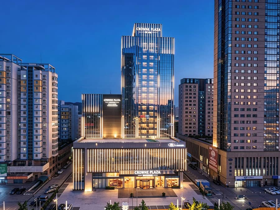 A modern building with a prominent sign for 'CROWNE PLAZA' and a glass facade.