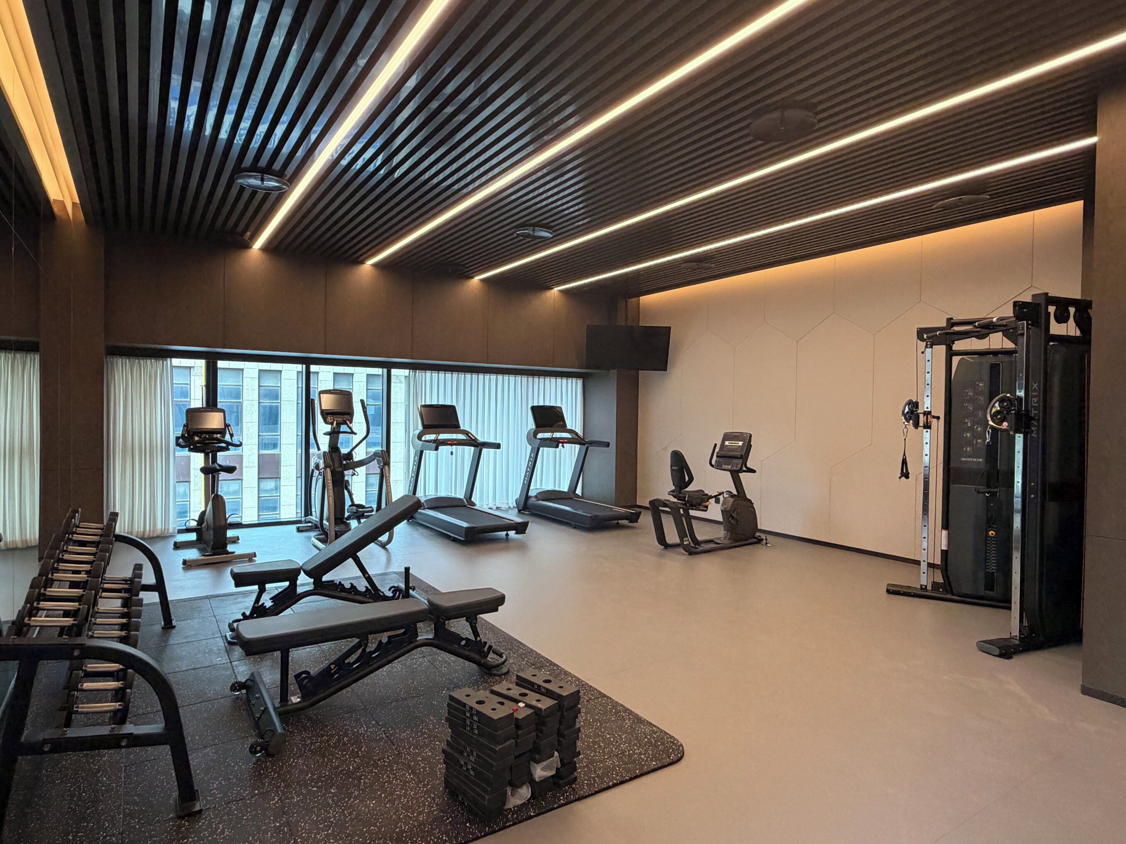 Un gimnasio moderno con cintas de correr, prensa de banca y una torre de pesas.