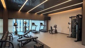 Un gimnasio moderno con cintas de correr, prensa de banca y una torre de pesas.