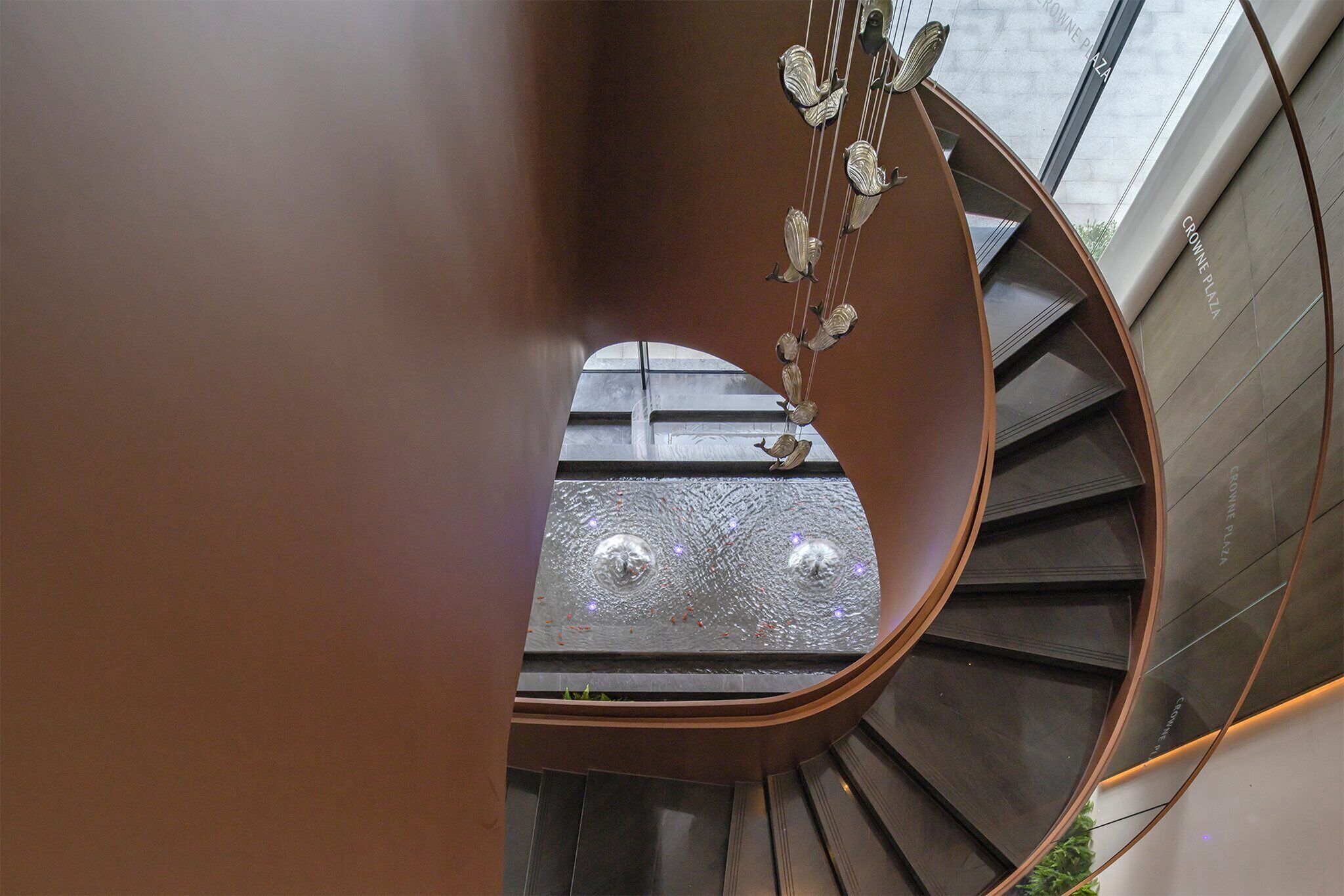 Een wenteltrap met een metalen leuning en een glazen balustrade.