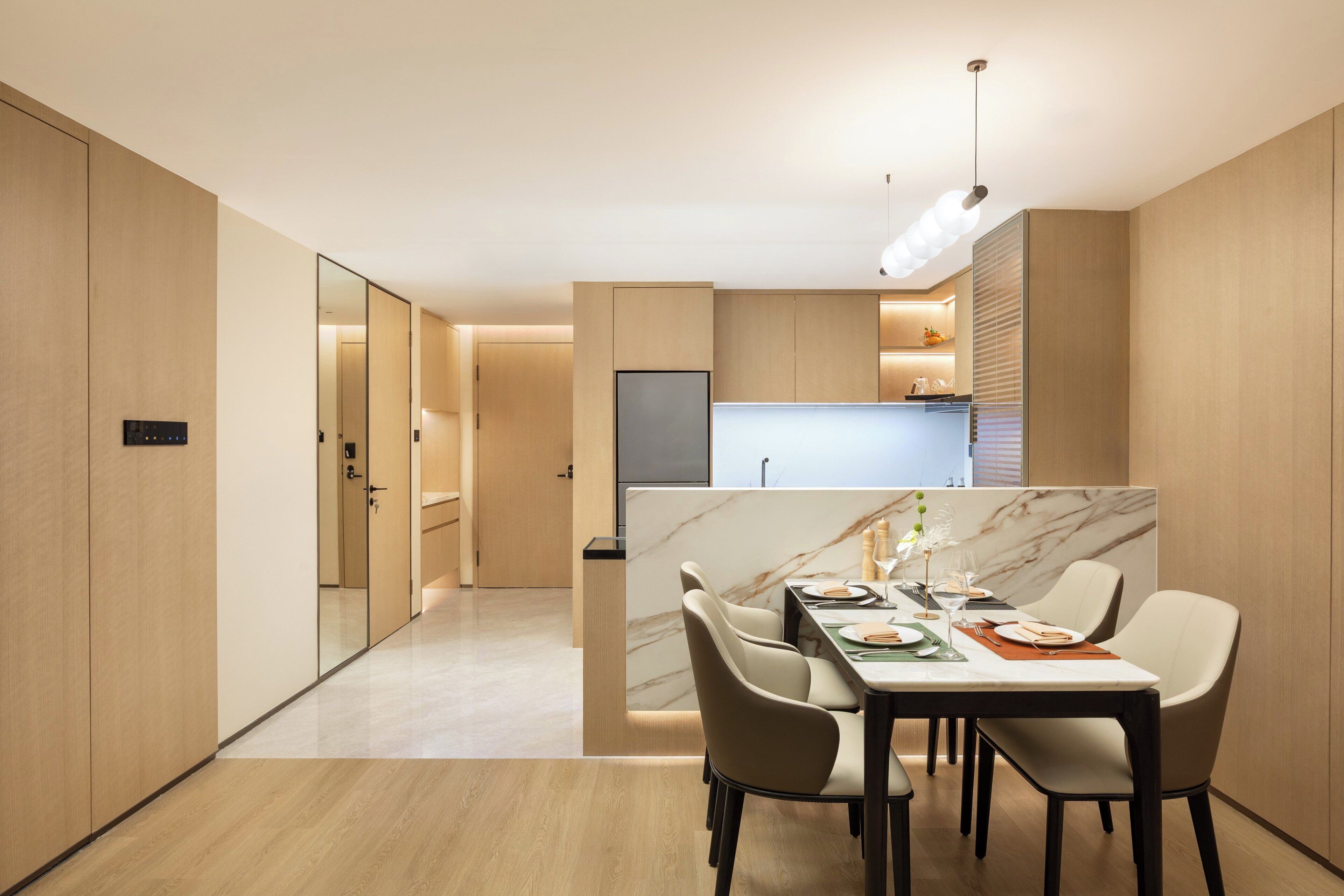 Un comedor moderno con una mesa de mármol, sillas de cuero y una cocina al fondo.
