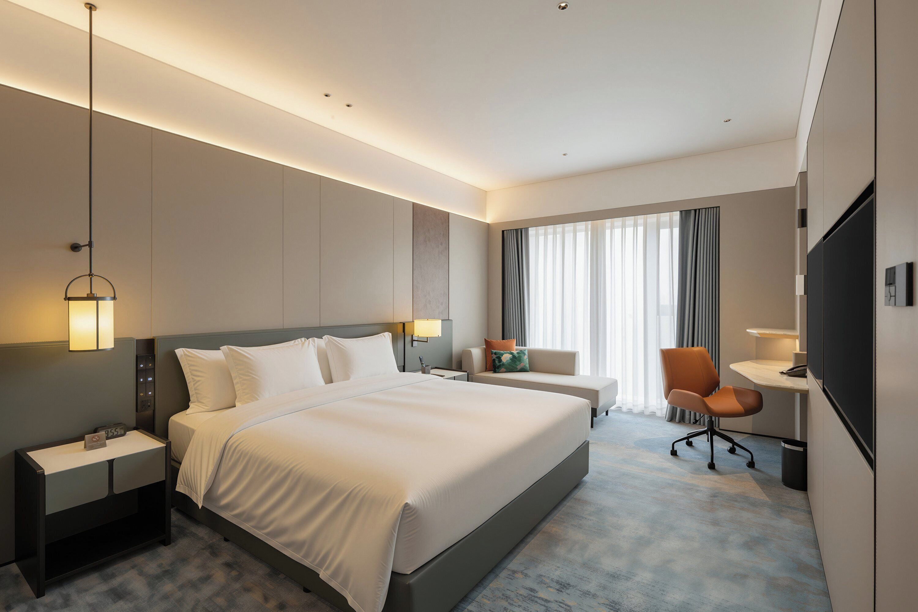 Une chambre d’hôtel avec un grand lit, des tables de chevet, un bureau, une chaise et un téléviseur.