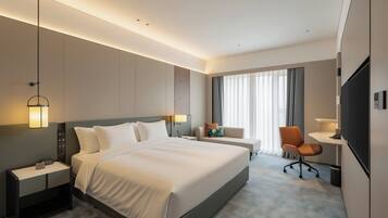 Une chambre d’hôtel avec un grand lit, des tables de chevet, un bureau, une chaise et un téléviseur.