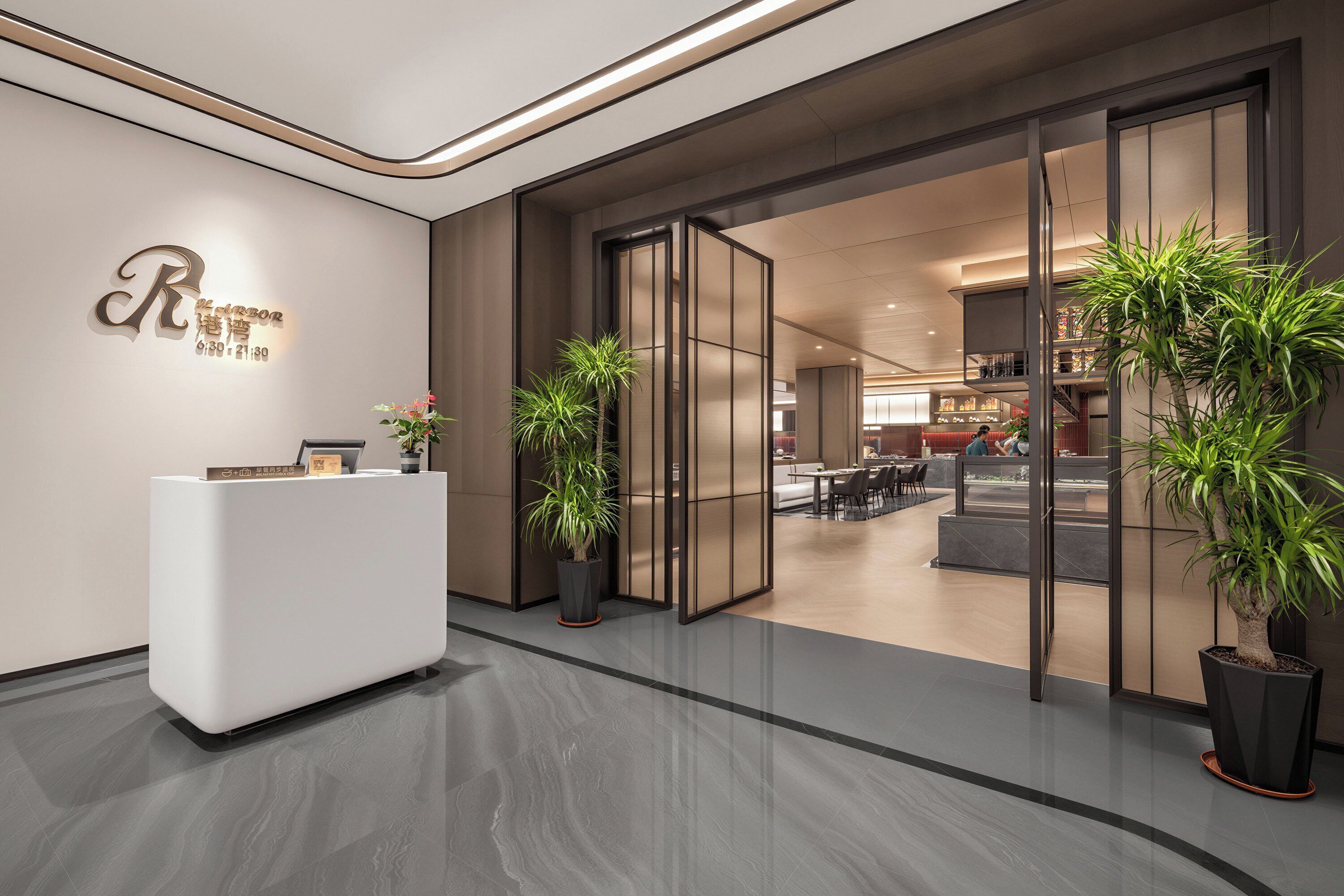 A reception area with a modern reception desk, a glass door entrance, and potted plants.