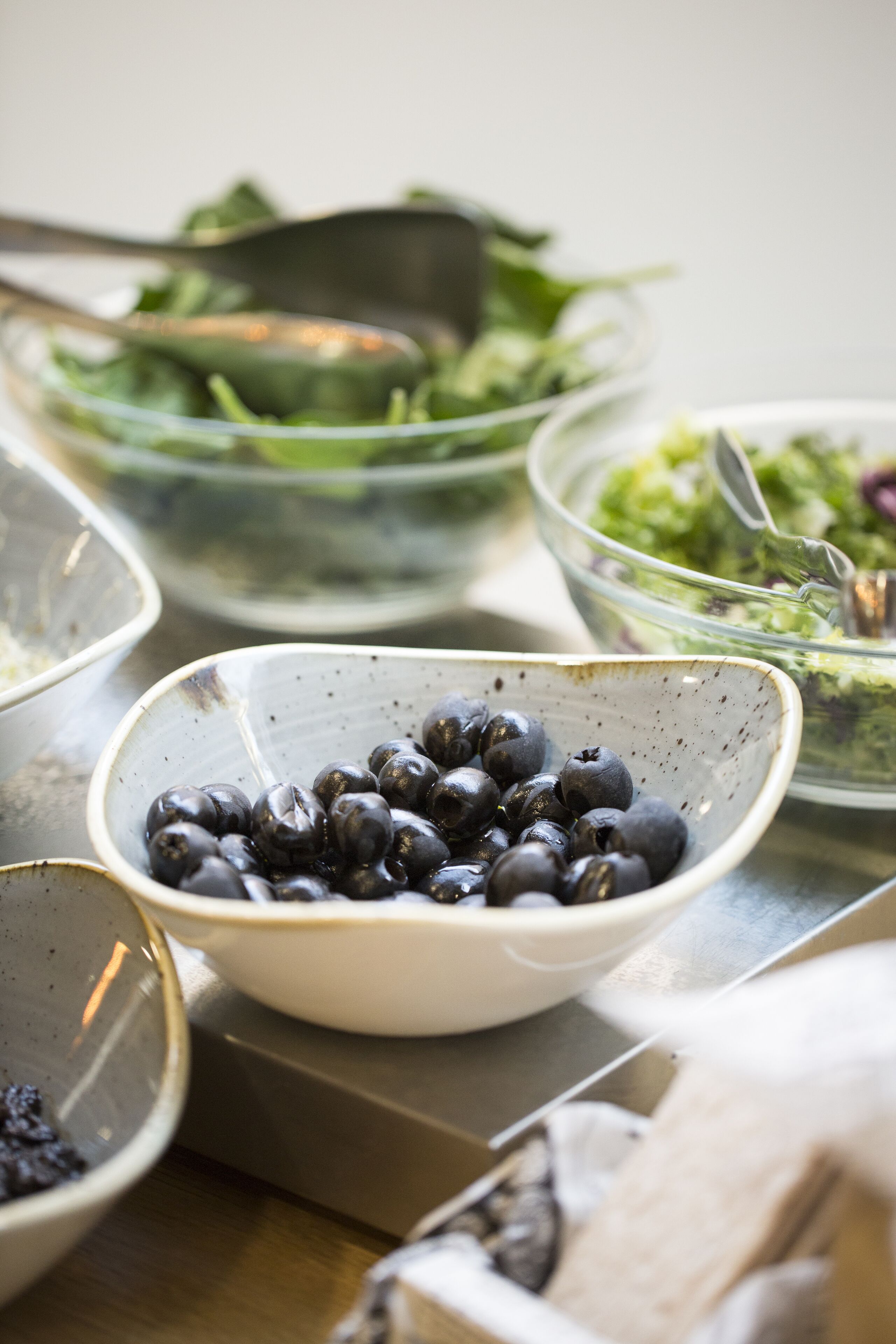 A table with various bowls containing food items, including a bowl of blueberries and a bowl of salad.