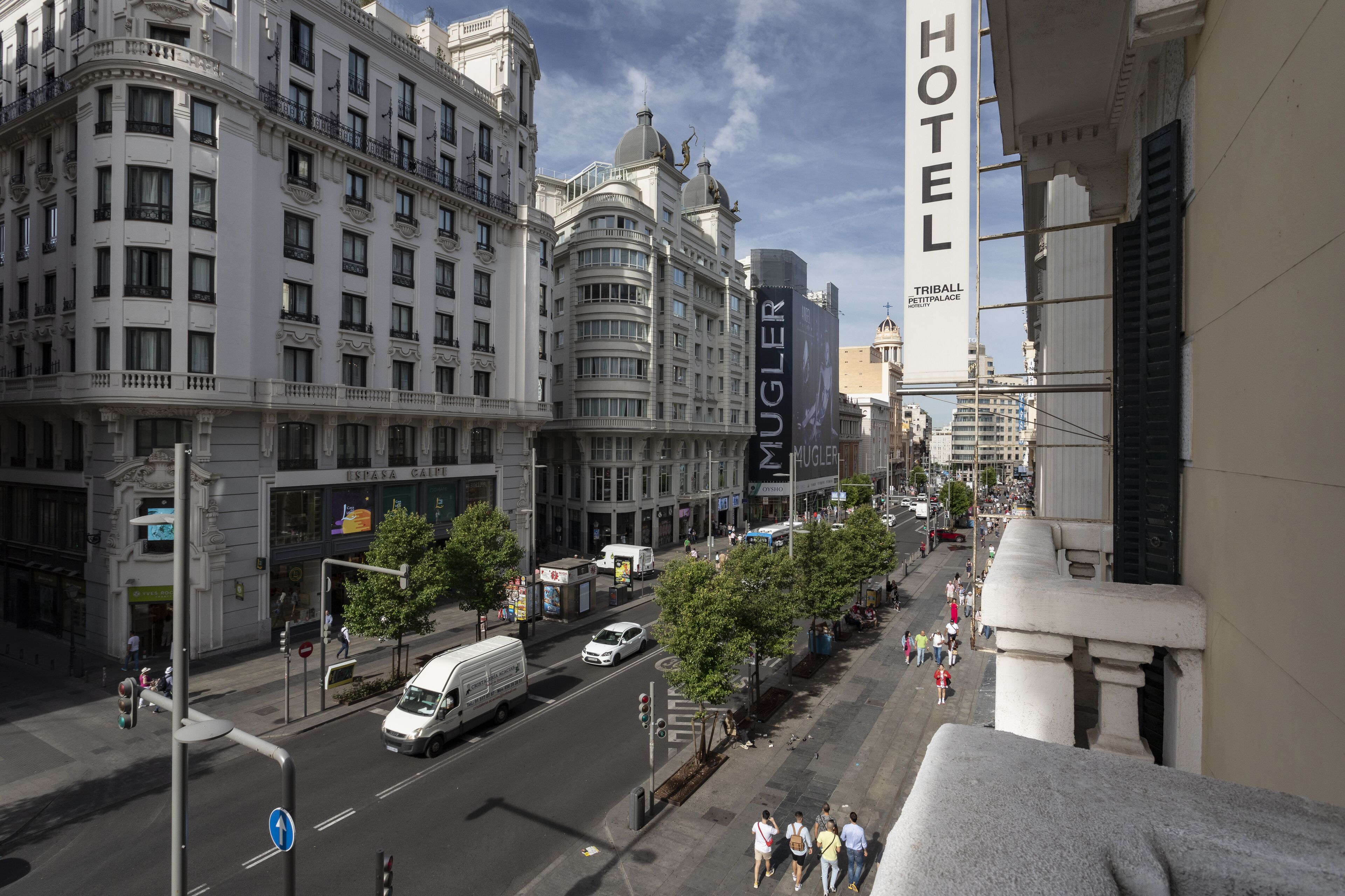 A multi-story hotel with a prominent 'HOTEL' sign, located in a busy urban street with pedestrians and vehicles.