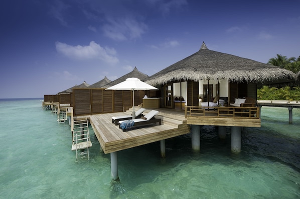 Overwater bungalows with thatched roofs, wooden deck, and lounge chairs. - Niva Kuramathi Maldives (Kuramathi Island)