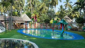A water park with slides, a pool, and tropical vegetation.