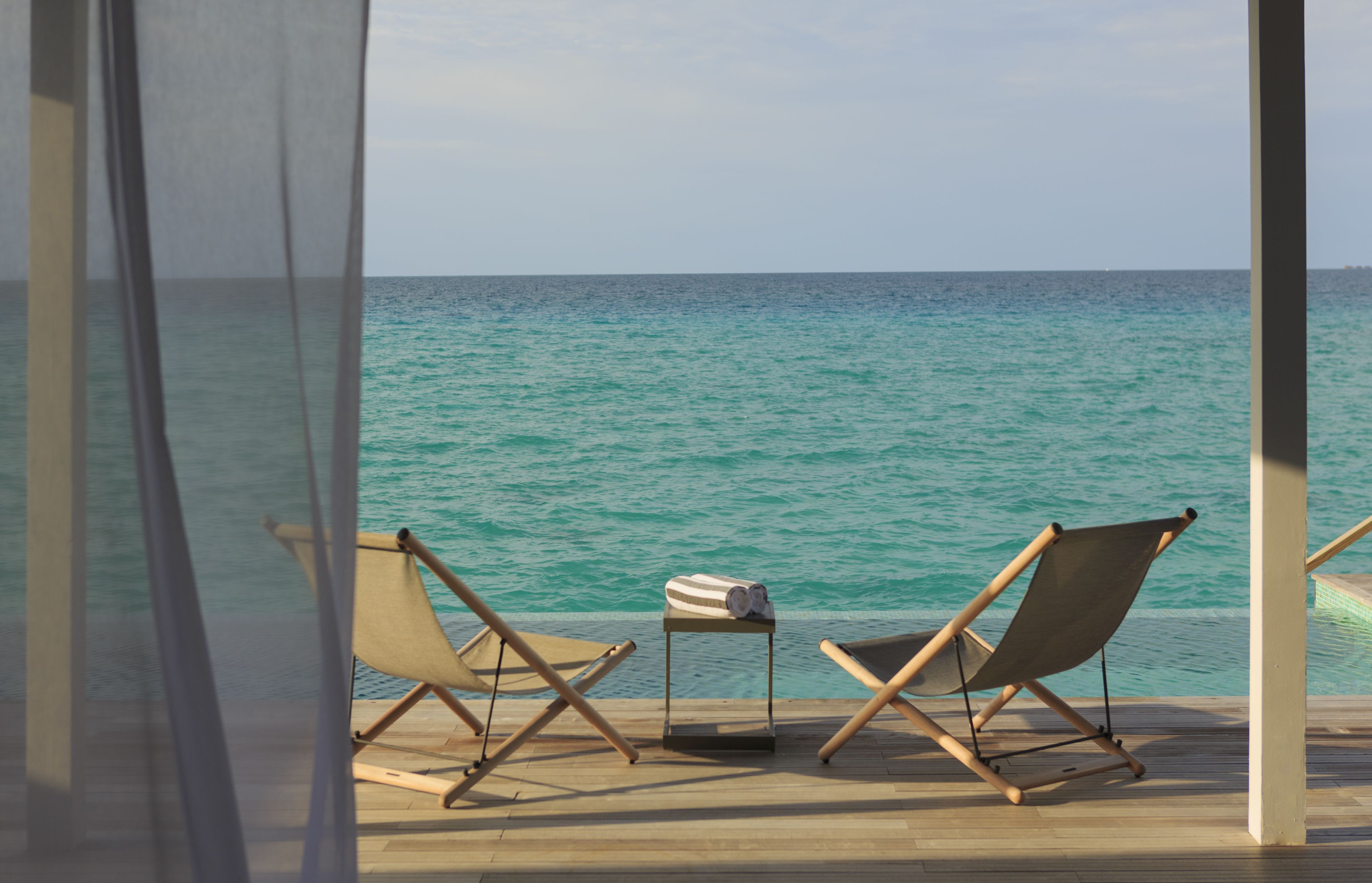 A wooden deck with two foldable chairs and a small table with a rolled-up towel.