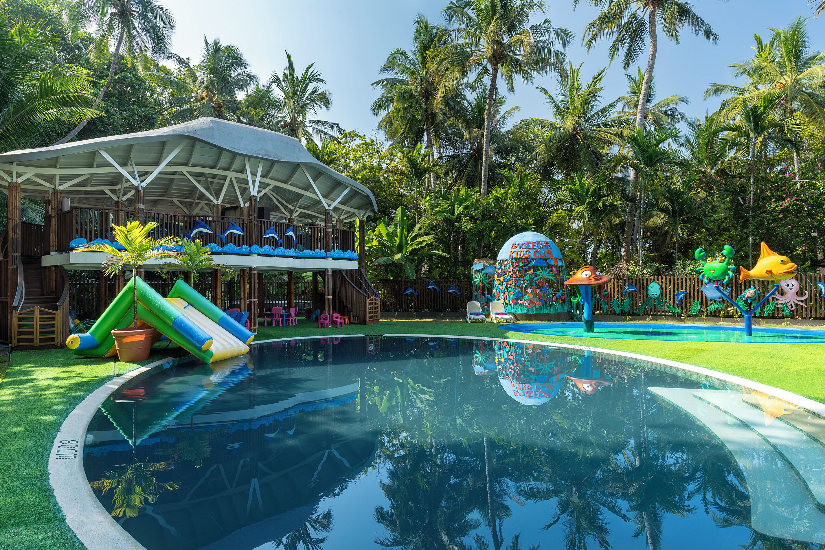 Una piscina con tobogán y zona de juegos infantiles con decoraciones coloridas.