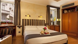 A hotel room with a bed, bedside table, lamp, and a view of the outside balcony. - La Fenice (Rome)