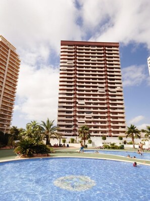A high-rise building with a pool area in front.